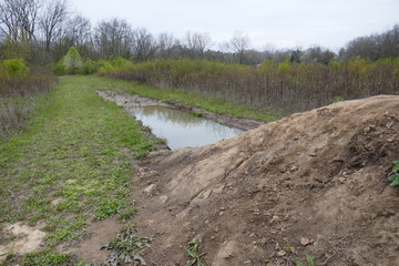Mound of dirt with water fill trench in natural parkland