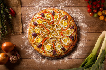Tasty portuguese pizza and cooking ingredients tomatoes basil on wood background. Top view.
