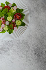Healthy food. The concept of vegetarian food. Fresh vegetable salad with radish slices, cherry tomatoes, cucumbers and lettuce leaves top view. Copy space text. No people