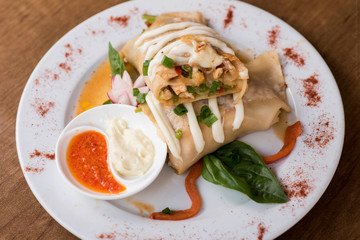 Canelone decorado con salsa en plato blanco   