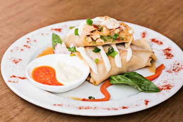 Canelone decorado con salsa en plato blanco   