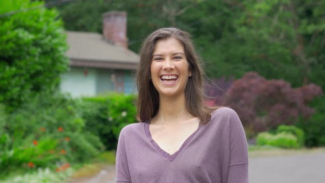 Attractive young woman not wearing bra looking and smiling at the camera while walking in the sun dressed scandalously