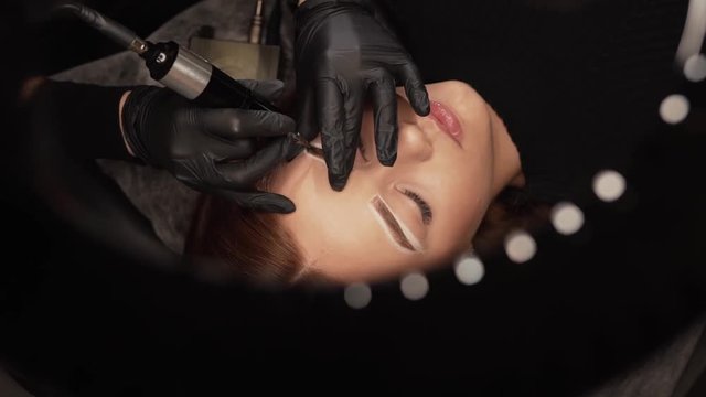 close-up of the hands of a master make eyelash extensions to a young girl