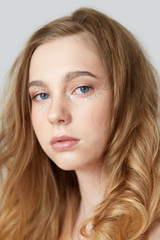 Fototapeta premium Young beautiful girl with light makeup and rhinestones under the eye.