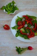 Healthy food. The concept of vegetarian food. Fresh vegetable salad with radish slices, red bell pepper, cherry tomatoes, cucumbers and lettuce leaves top view. Summer fresh salad with space for text