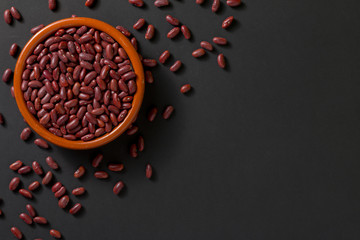 Top view of a bowl with red beans on a black background.