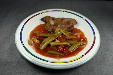 Traditional grilled pork steak with local tomato sauce, boiled string peanut and sliced fresh onion on the plate. Famous main course in Asia restaurant.