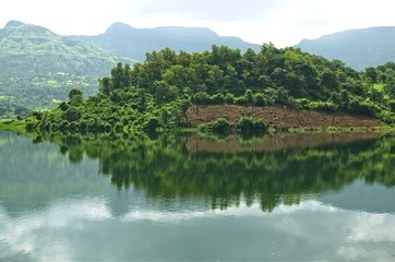 Fototapeta premium Reflection of a hill covered with green trees