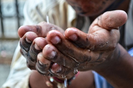 A poor beggar is taking water in hand to drink