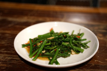 Chayote leaves with chili in Oyster sauce on white plate