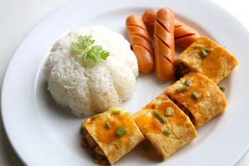 Close up Omelette rice with sausages served on a white plate on a white table