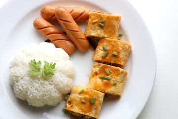 Close up Omelette rice with sausages served on a white plate on a white table
