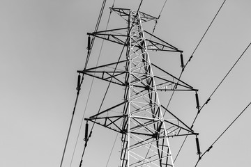 High power electricity poles connected to smart grid at clear sky. Black and white photo.