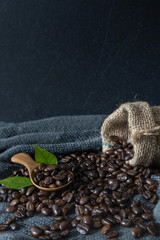 Coffee beans with leaf on vintage black fabric background.