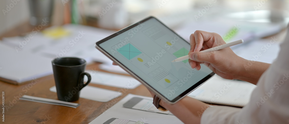 Wall mural side view of professional ui developer concentrating on his project with digital tablet and paperwor