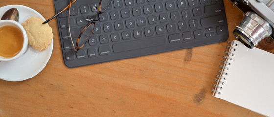 Top view of portable workspace with wireless keyboard, glasses, notebook and snack