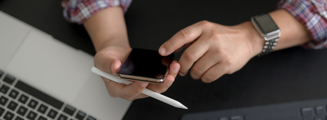 Overhead shot of businessman touching on smartphone while working with digital devices