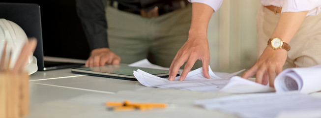Cropped shot of two engineers consulting on their project with mock-up tablet and paperwork