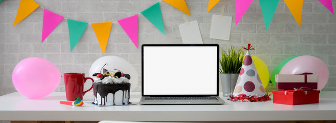 Online Birthday celebration concept with blank screen laptop, cake and decorations