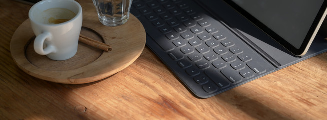 Cropped shot of workspace with digital tablet and coffee cup on wooden counter bar