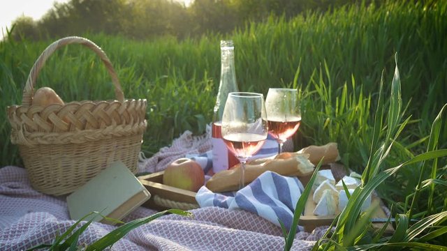 picnic basket with the food and bottle of wine on a grass at the field
