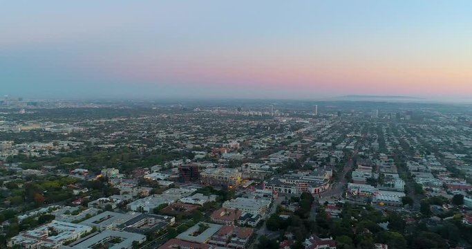 Overlooking the Hollywood area, the Downtown skyline, Fairfax, La Brea, Beverly Hills, Century City Twin Towers and Culver City, in Los Angeles, colorful dusk, in CA, USA - Aerial, pan drone view