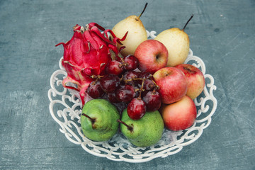 fresh fruits on white basket, dragon fruit, apple, pears and grapes