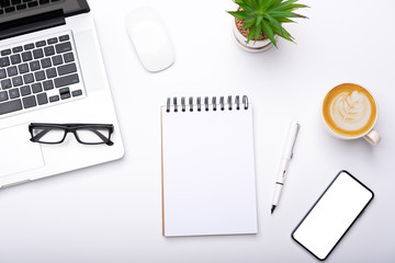 Top view with working desk with laptop,cellphone,notebook pencil coffee cup and eyeglasses in the office.