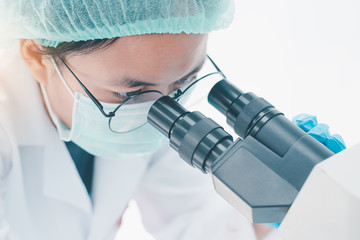 female medical researcher looking at a microscope in a medical laboratory. Medical experimental...