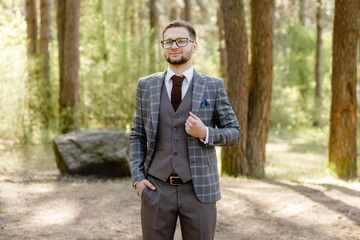Fototapeta na wymiar student with glasses in a suit posing in the forest