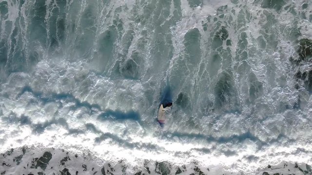 A determined surfer paddles out to sea against some strong waves.