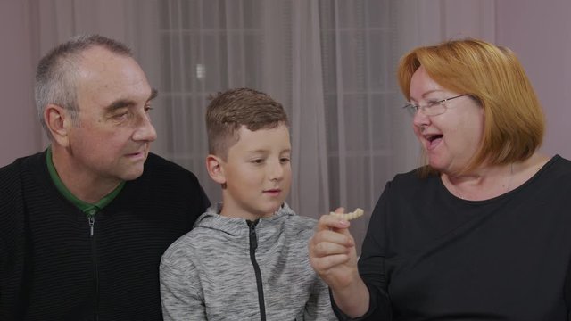 Happy toothless grandfather, granny and grandson together are laughing in front of the camera. Closeup.