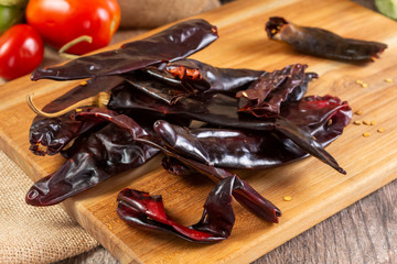A closeup view of a pile of dried guajillo chili peppers on a cutting board.