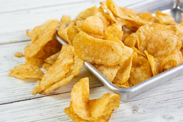 A view of a pile of potato chips on a metal tray.