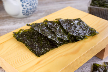 A view of several squares of dried seaweed snacks on a sushi table, in a still life setting. © DAVID