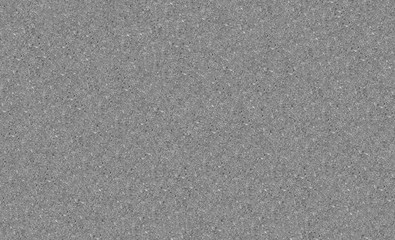 Top view of gray textured asphalt road surface. Patterns of small sand grains form a solid road structure. Monochrome background of empty roadway.