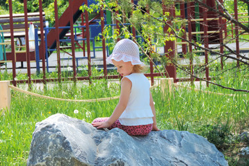 girl sitting on a huge boulder in the summer park