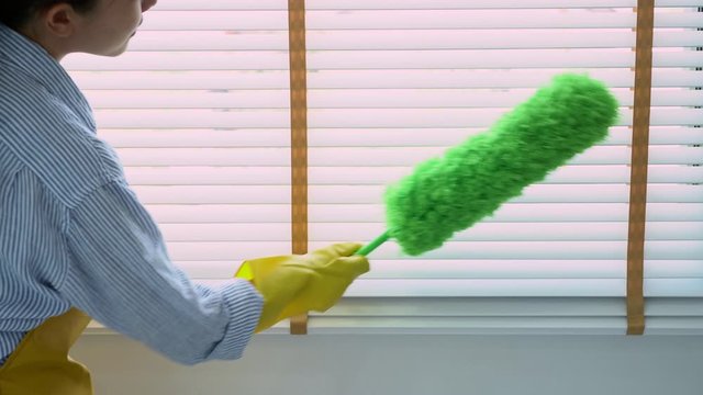 4k video of Housekeeper Young female spring cleaning house interior holding a duster for wiping dust dusting furniture at home