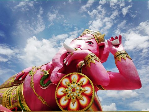 Wat Saman Rattanaram, Buddhist temple in Thailand. Giant pink statue of a Hindu god. Semi-sitting, reclining side With his left hand holding a broken tusk Right hand holding a lotus flower.