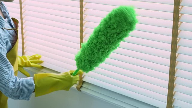 4k video of Housekeeper Young female spring cleaning house interior holding a duster for wiping dust dusting furniture at home