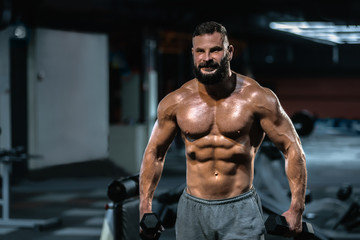 Fototapeta na wymiar Handsome man with perfect muscular body training hard in gym