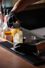 bar tender with gloves preparing mixed drink cocktail