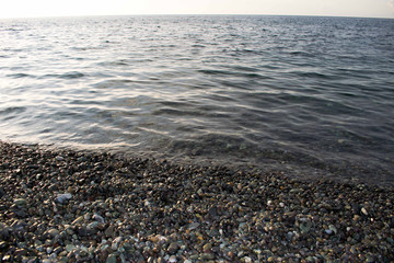 Vast ocean with smooth cobblestones or smooth pebbles. Clear water beach