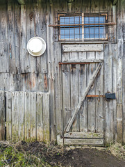 old weathered wooden shed wall with closed door and window
