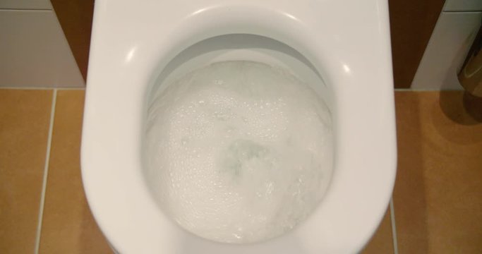 Pressing the toilet flush button, tilt-down to flushing with water in slow motion