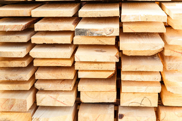 Stack of new wooden studs at the lumber yard. Timber on the construction site to dry. Background of sawed and processed wood of coniferous breeds.
