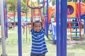 Asian boy playing monkey bars in the playground with fun.