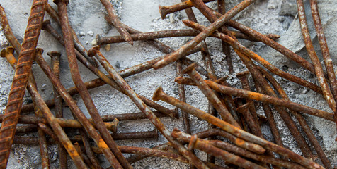 Background old rusty nails and rebar close-up in blurred selective focus on a light background.