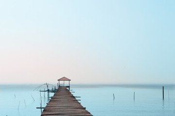 Fototapeta na wymiar wood bridge move to small pavilion on the sea with blue sky adn fog