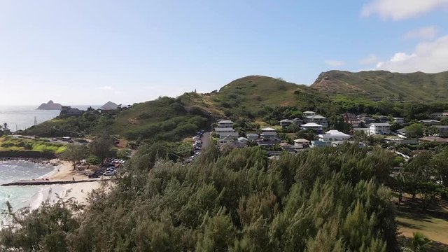 Aerial drone flying over trees revealing beautiful Lanikai Beach in Hawaii.